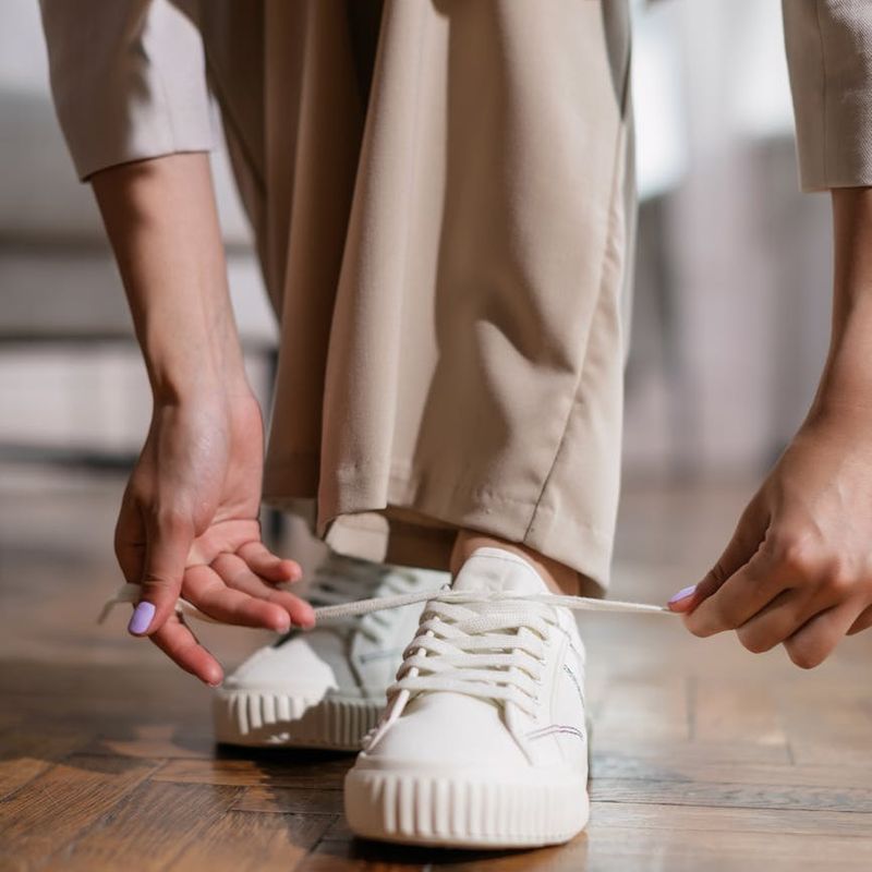 Person hands tying shoelaces on white sneakers